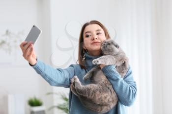 Young woman taking selfie with her cute cat at home�