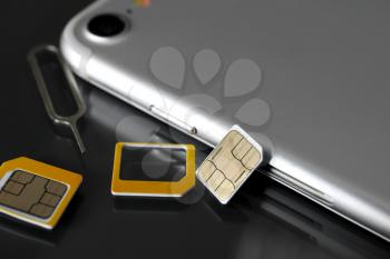 Mobile phone with sim cards and key on dark table�