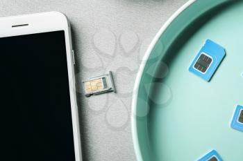 Plate with sim cards and mobile phone on grey background�