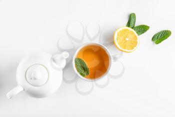 Teapot, cup of hot beverage, lemon and mint on white background�