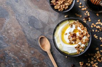 Bowl with tasty yogurt, honey and oatmeal on dark background�