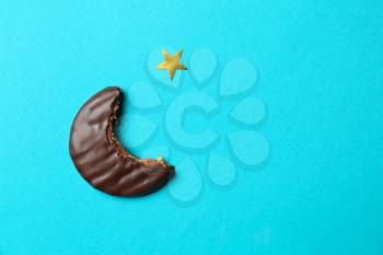 Bitten cookie in shape of half-moon as symbol of Islam on color background�