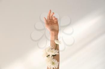 Female hand with white flowers on light background�