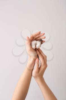 Female hands with cotton flower on light background�