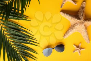 Summer composition with tropical leaves, starfish and sunglasses on color background�