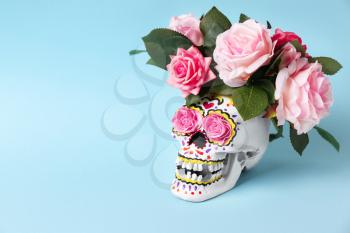 Painted human skull with flowers for Mexico's Day of the Dead on color background�