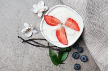 Bowl with tasty vanilla yogurt and strawberry on table�