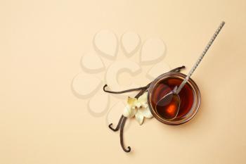 Bowl of vanilla extract on color background�