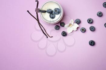 Jar of vanilla yogurt with blueberry on color background�