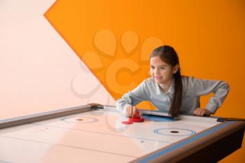 Little girl playing air hockey indoors�