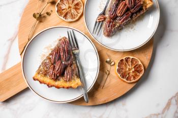 Wooden board with tasty pecan pie on light table�