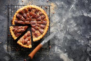 Cooling rack with tasty pecan pie on grey background�