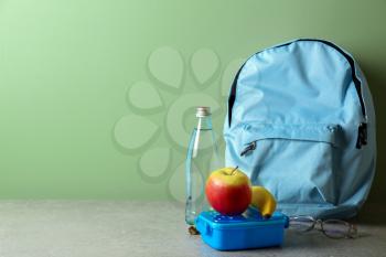 Schoolbag and lunch box with tasty food on table�