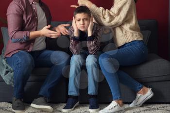 Sad little boy covering ears while his parents arguing at home�