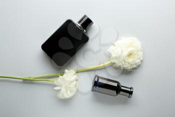 Bottles of perfume and flowers on light background�