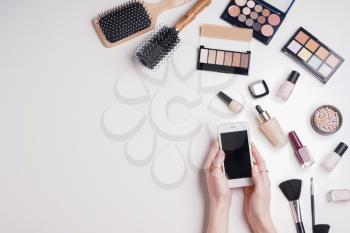 Beauty blogger with mobile phone and makeup cosmetics on white background�