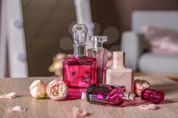 Bottles of female perfume and flowers on wooden table�