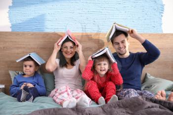 Happy family reading books in bed�