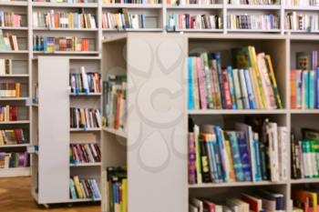 Many books on shelves in modern library, blurred view�