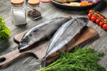 Board with tasty raw mackerel fish on wooden table�