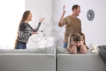 Sad little girl and her quarreling parents at home�
