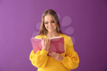 Beautiful young woman with book on color background�