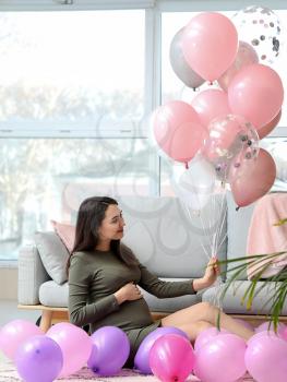 Beautiful pregnant woman with air balloons at home�