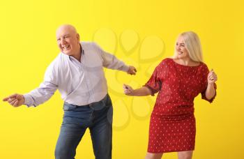 Cute elderly couple dancing against color background�