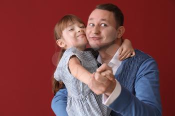 Father and his cute little daughter dancing against color background�