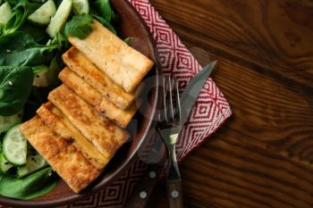 Tasty salad with tofu cheese on wooden table�