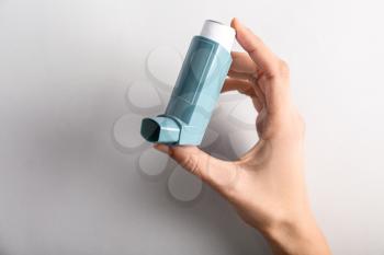 Female hand with inhaler against asthma on light background�