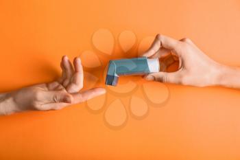 Female hands with inhaler against asthma on color background�