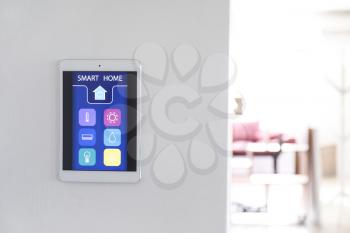 Tablet computer with smart home application on wall�