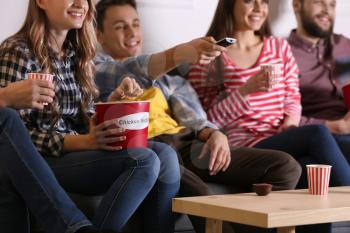 Group of friends eating nuggets while watching TV at home�