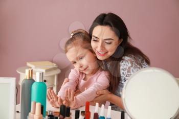 Cute daughter with mother making manicure at home�