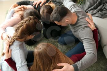 Group of people praying together indoors�