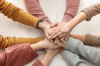 Group of people putting hands together at table�