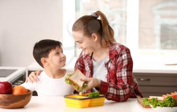 Mother packing school lunch for her little son at home�