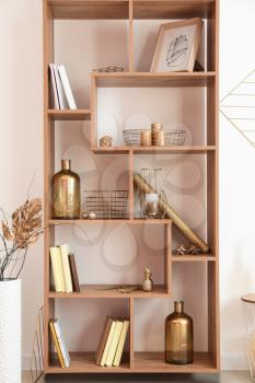 Wooden shelving unit with golden decor near white wall�