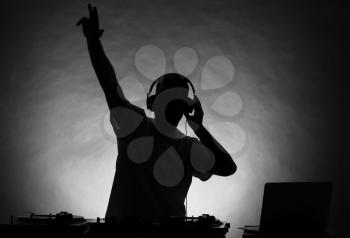 Silhouette of male DJ playing music on grey background�