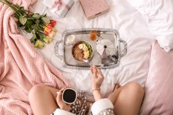 Young woman having breakfast on bed�