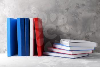 Many books on table against grey background�