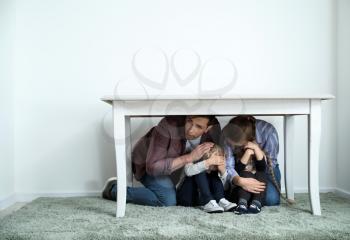 Family under table during earthquake indoors�
