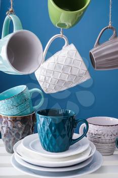 Shelf with different tea cups and saucers on color background�