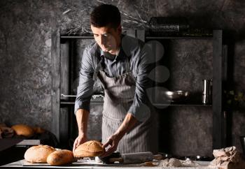 Young man with freshly baked bread in kitchen�