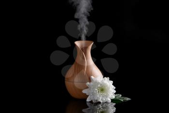 Aroma oil diffuser and flower on dark background�