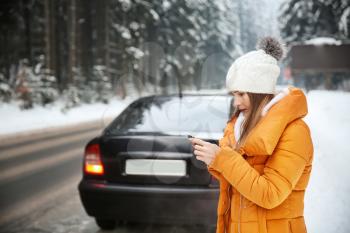 Young woman with phone near road at winter resort�