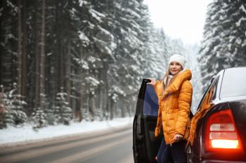Young woman near car at winter resort�