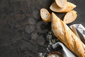 Cut French bread with flour on grey background�