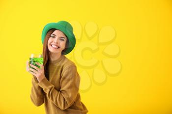 Beautiful young woman in green hat and with mug of beer on color background. St. Patrick's Day celebration�